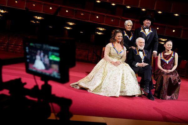 Kennedy Center Honors는 전염병으로 인해 지연되고 변형되었습니다. 올해의 수상자는 Debbie Allen, Dick Van Dyke, Midori가 앉아 있고 Joan Baez와 Garth Brooks가 서 있습니다.